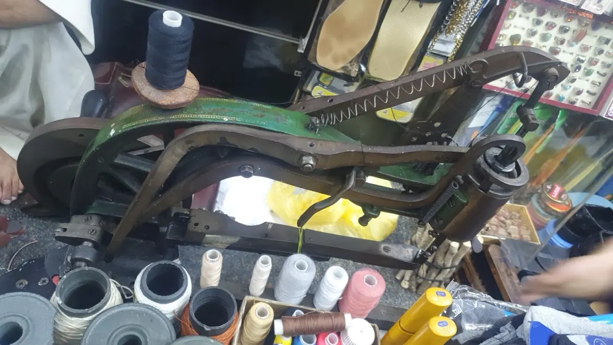 The repair bench with sewing machine, shoes and leather tools